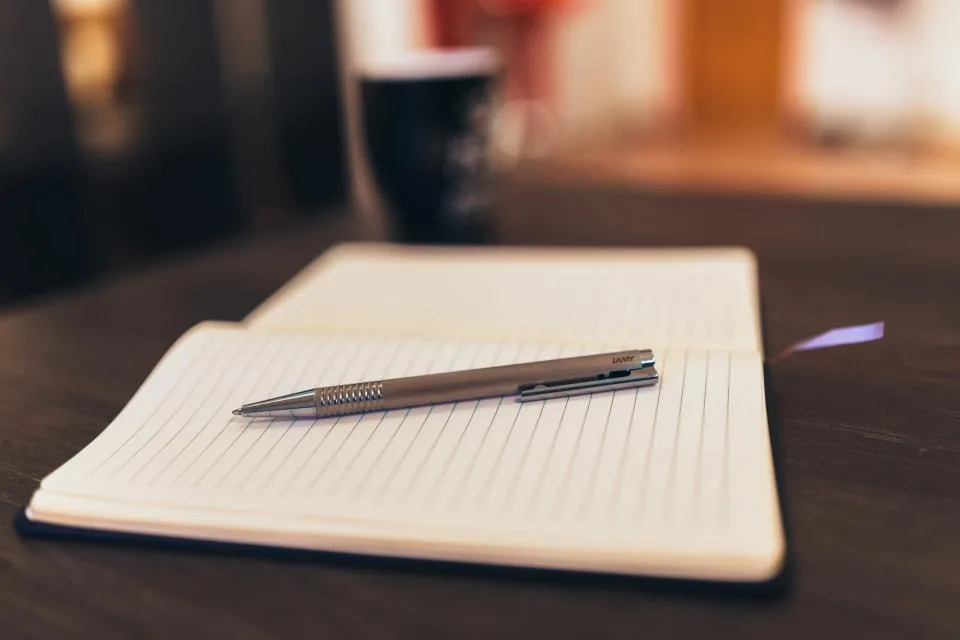 Caderno aberto com uma caneta sobre a mesa